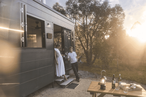 Couple enjoying a wine-filled sunset outside their eco-friendly cabin in the Adelaide Hills – perfect inspiration for what to do in Adelaide Hills.